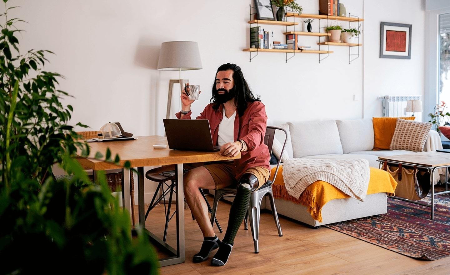 Man with prosthetic leg working at table with laptop