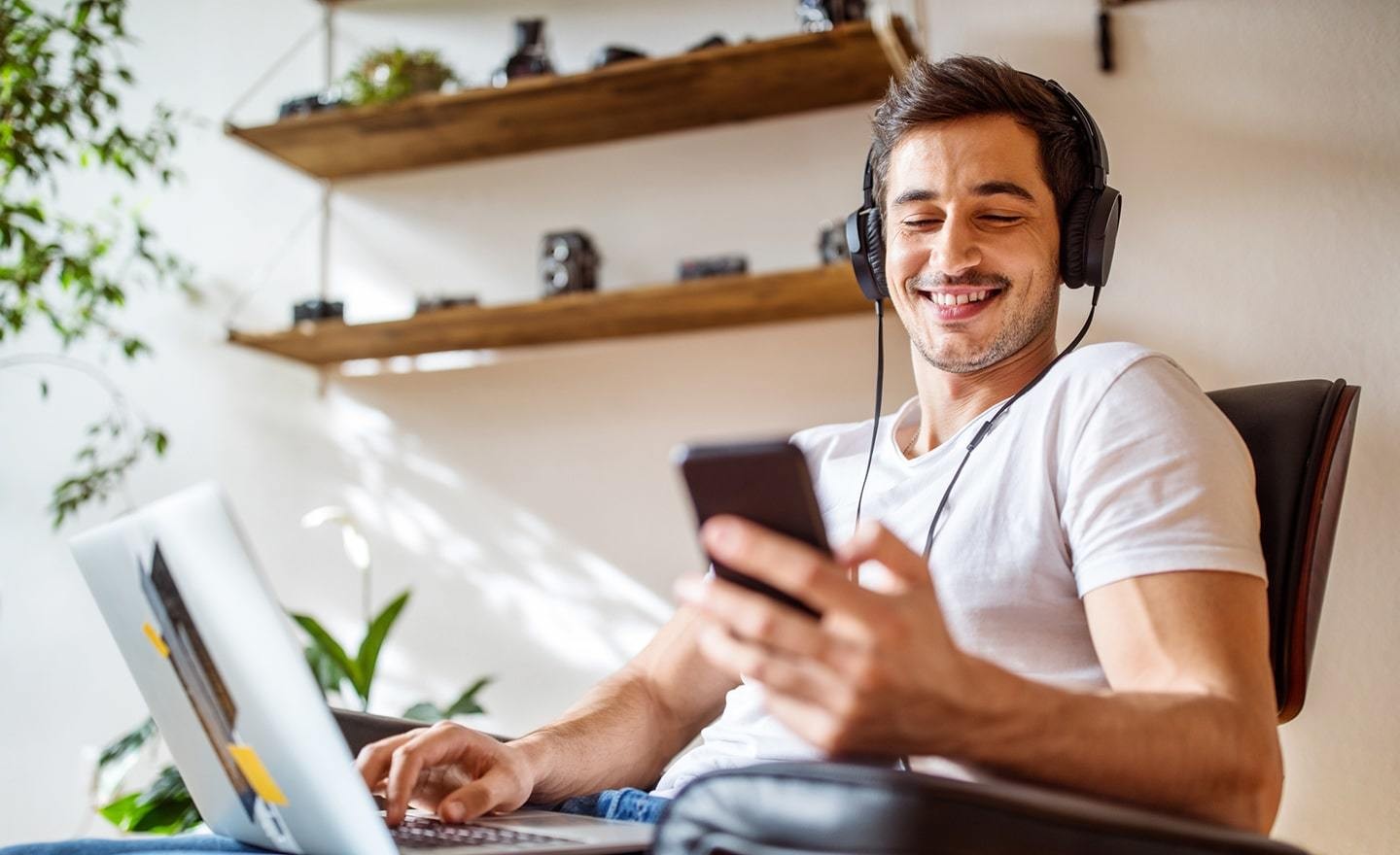 Man working on laptop checking phone