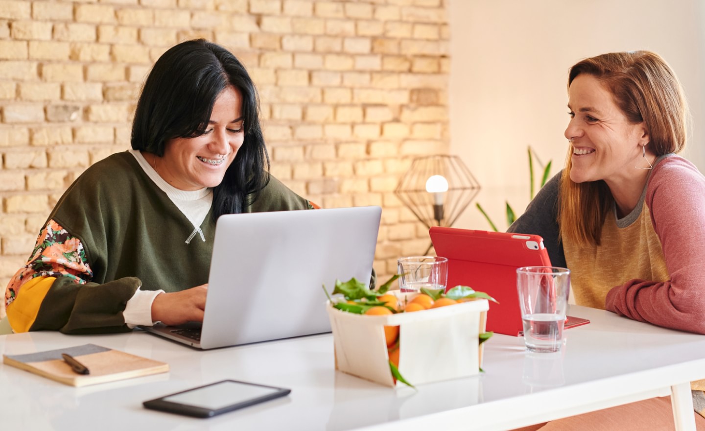 Photo of two female colleagues working at table