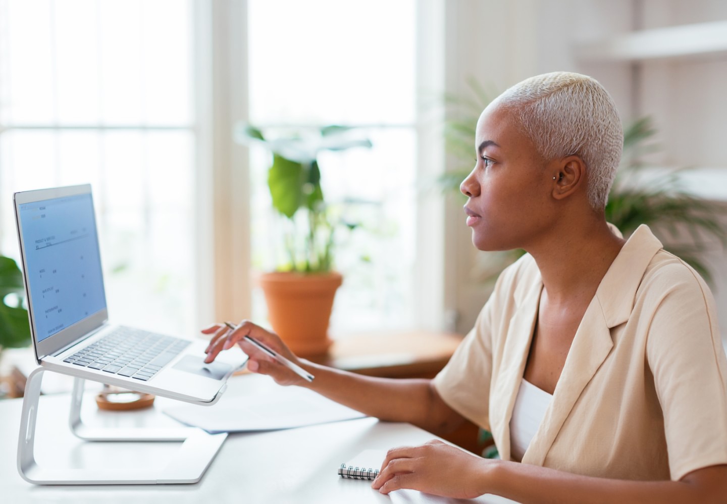 Side view of a woman sitting at table and browsing data on laptop in a modern workspace