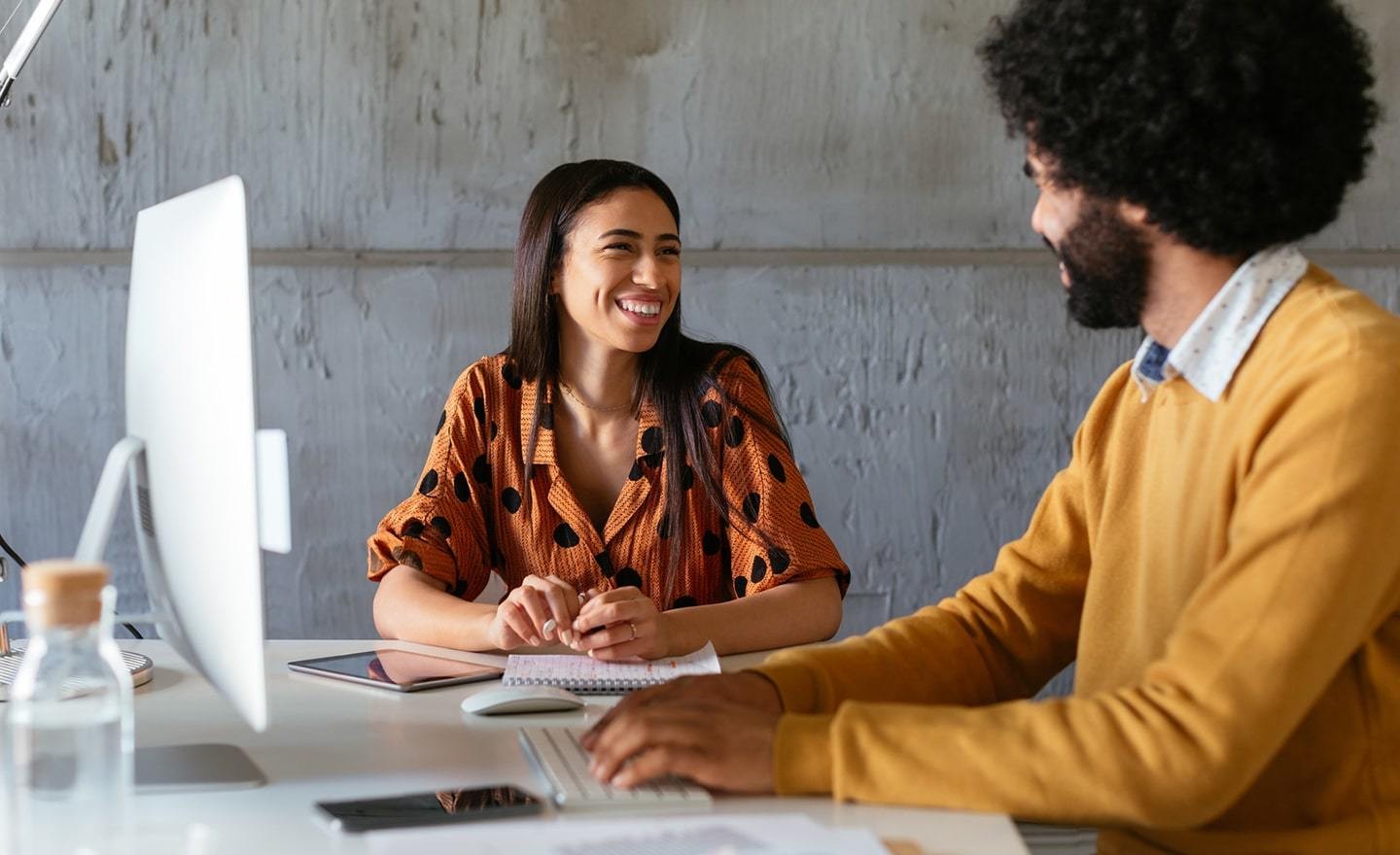 Two people speaking in front of a computer