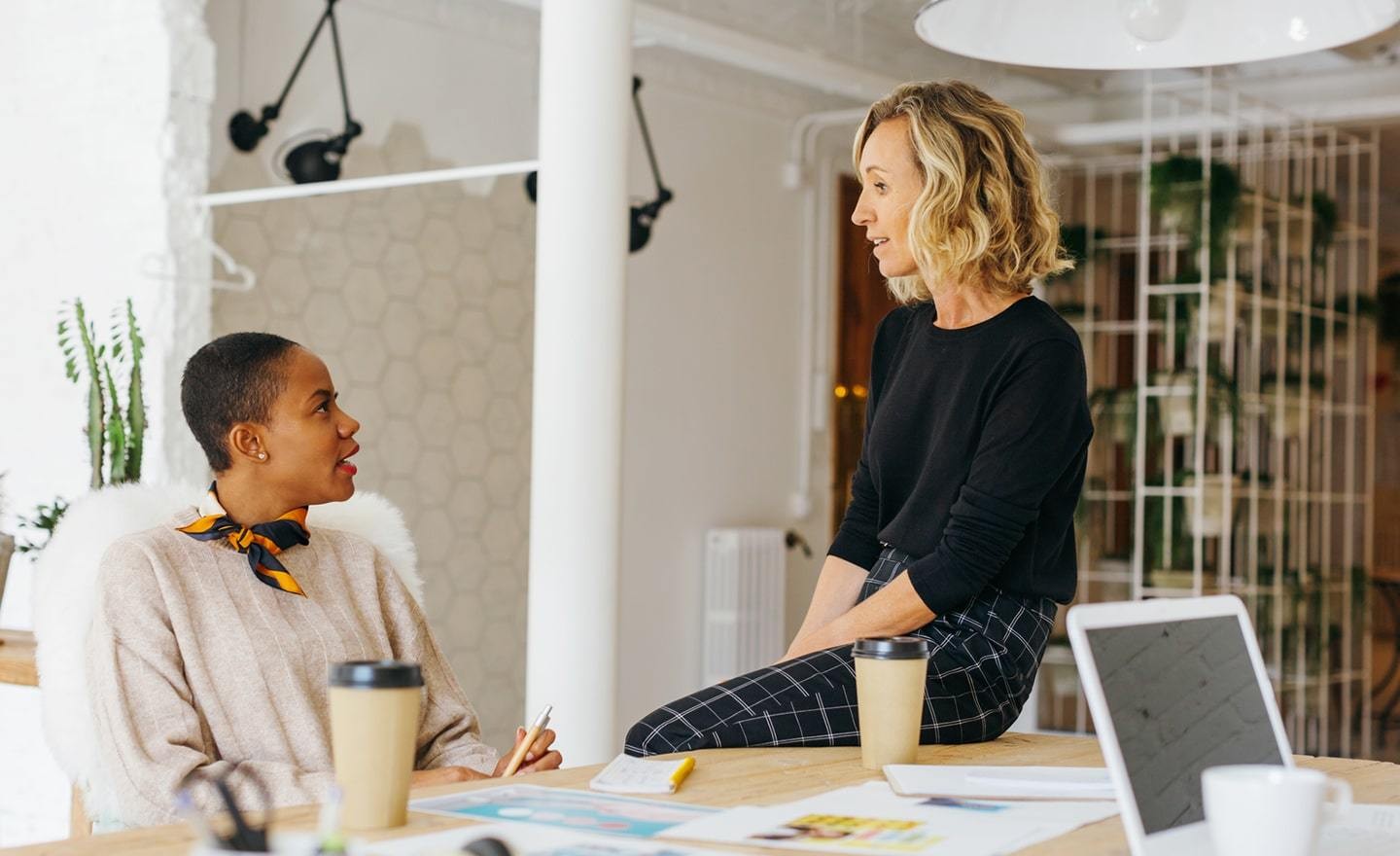 Two women coworkers in conversation at a desk