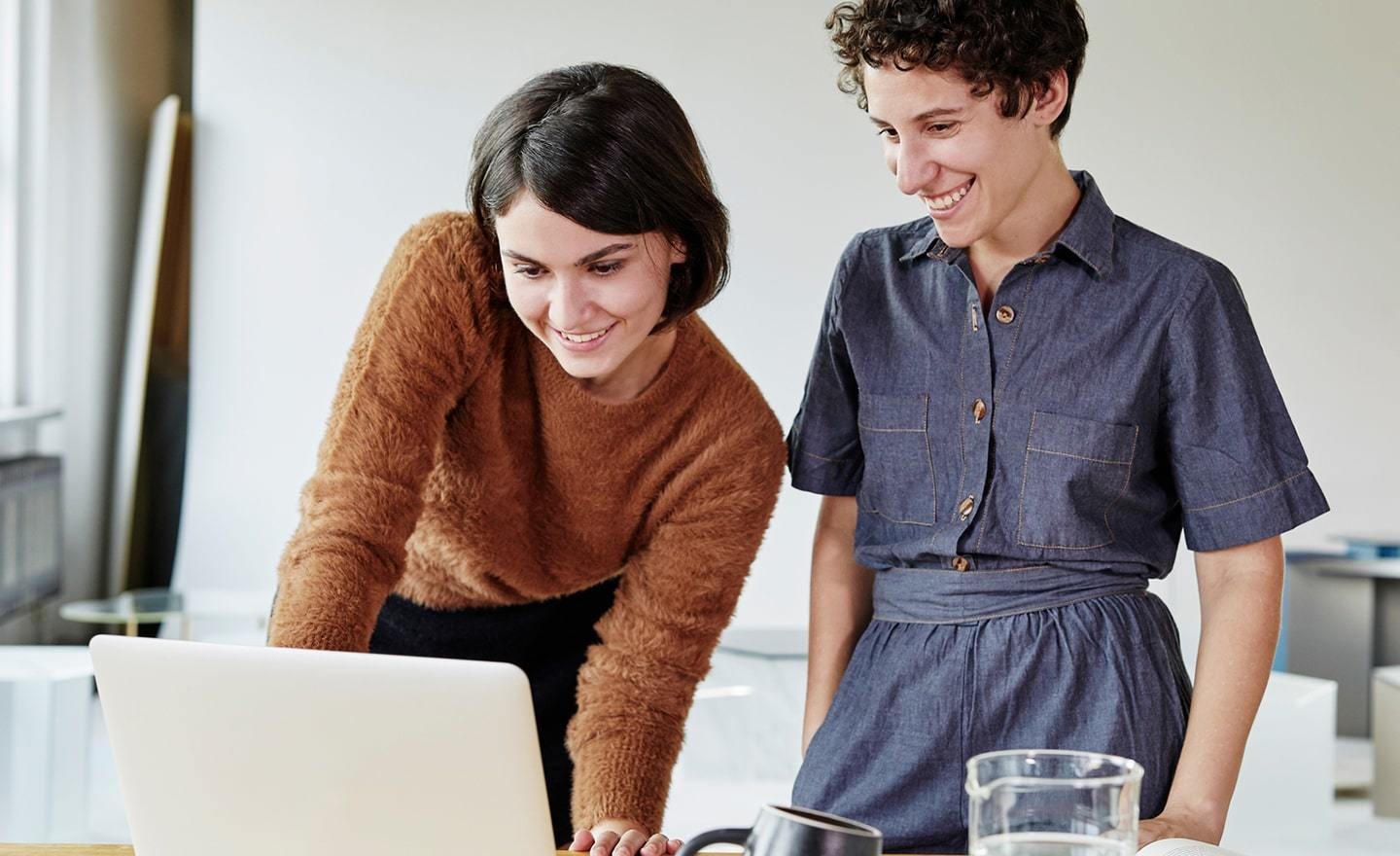 Two women standing over laptop