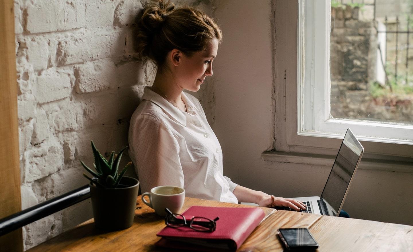 Woman on laptop sitting by window