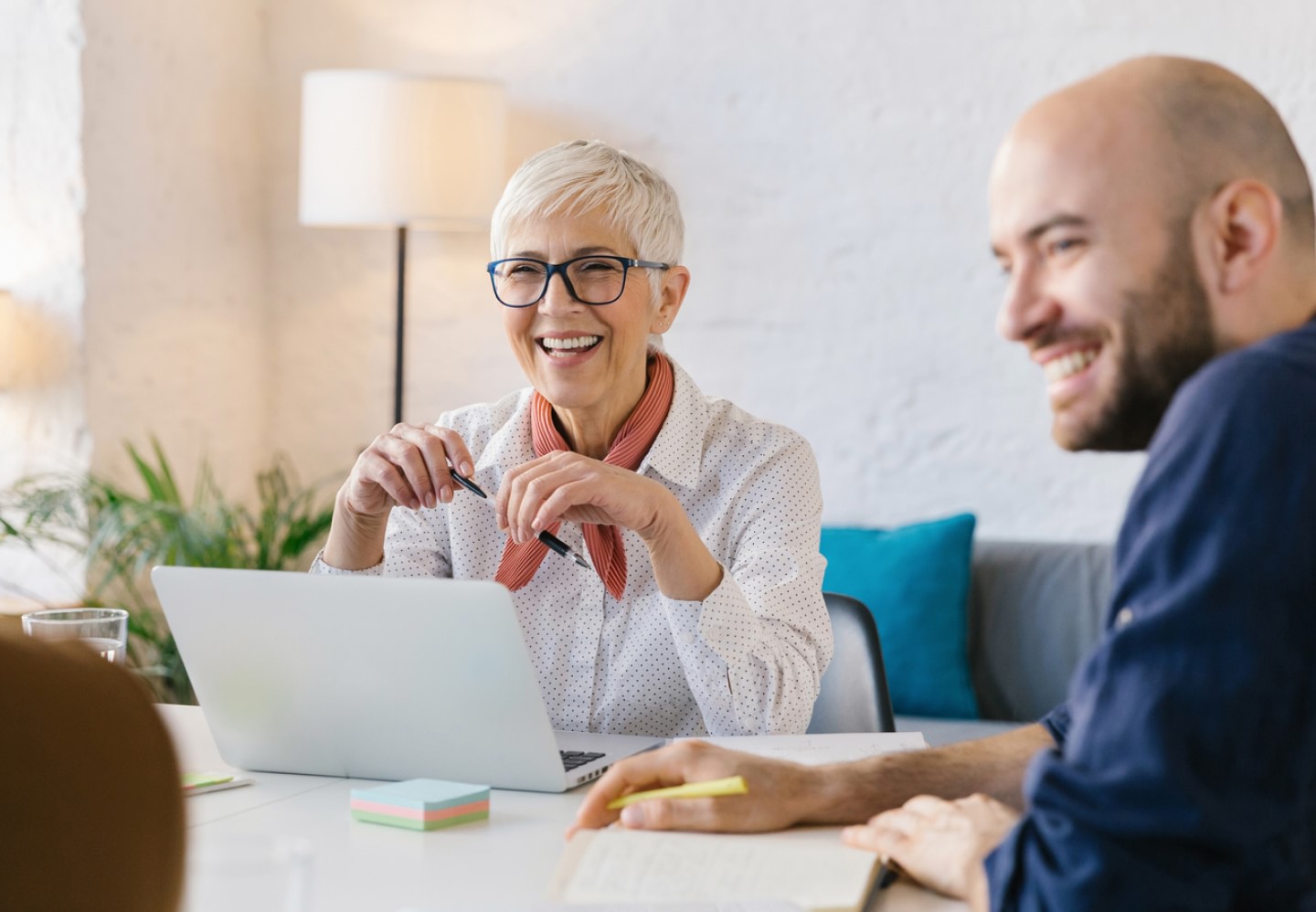 Woman sitting behind laptop smiling next to man sitting at a desk together