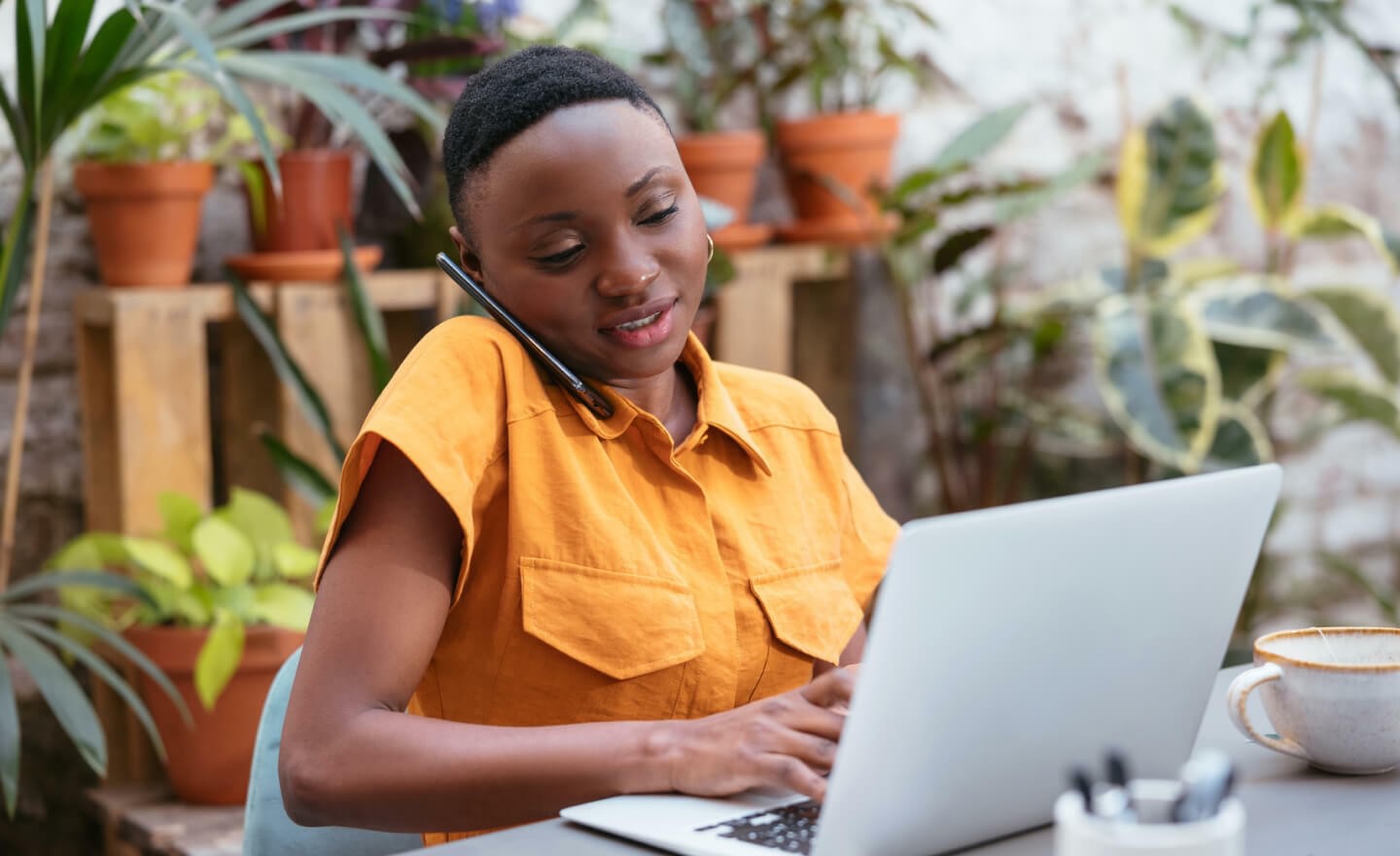 Woman taking a phone call while typing on laptop