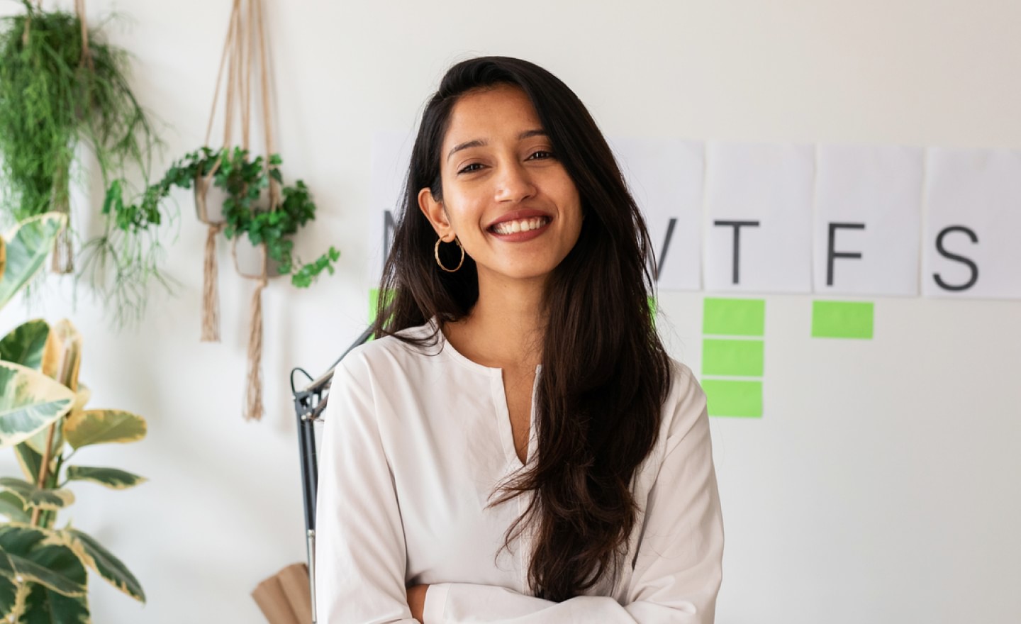 Woman wearing white top smiling in an office setting