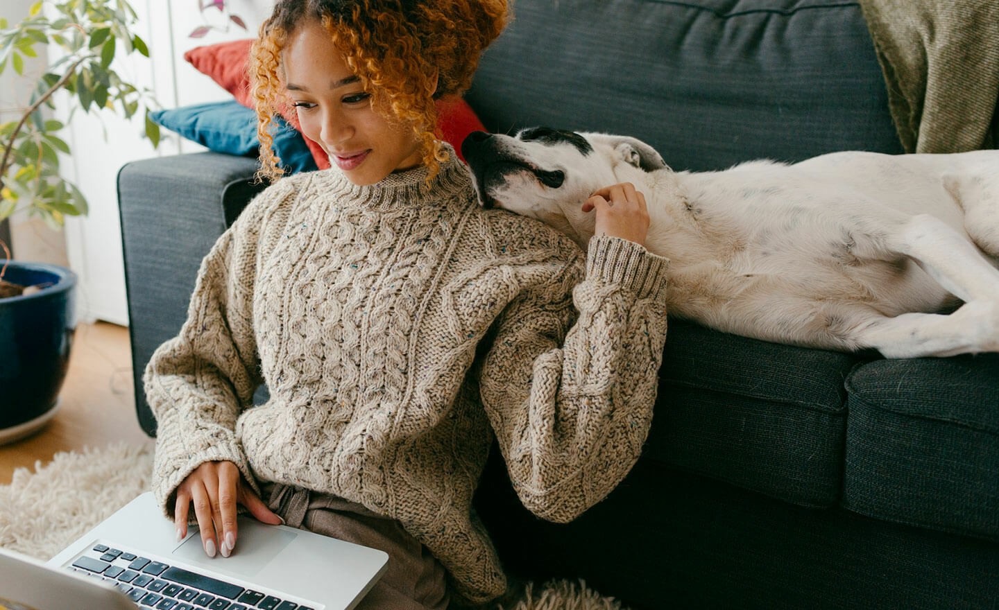 Woman working from home on laptop with dog