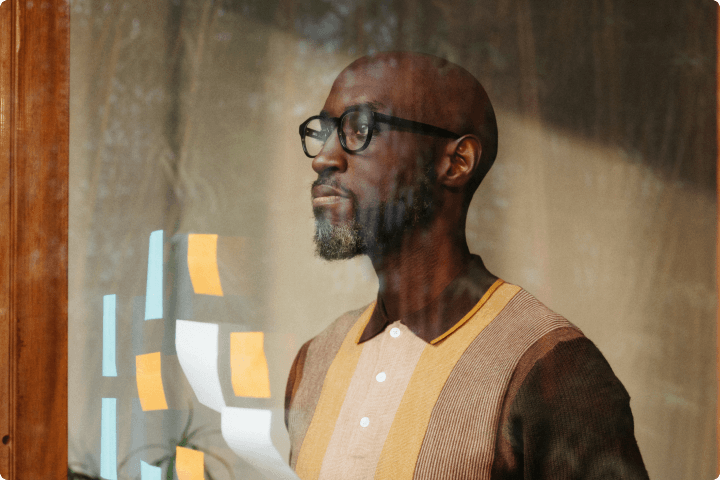 Man reviewing sticky notes posted on a glass wall