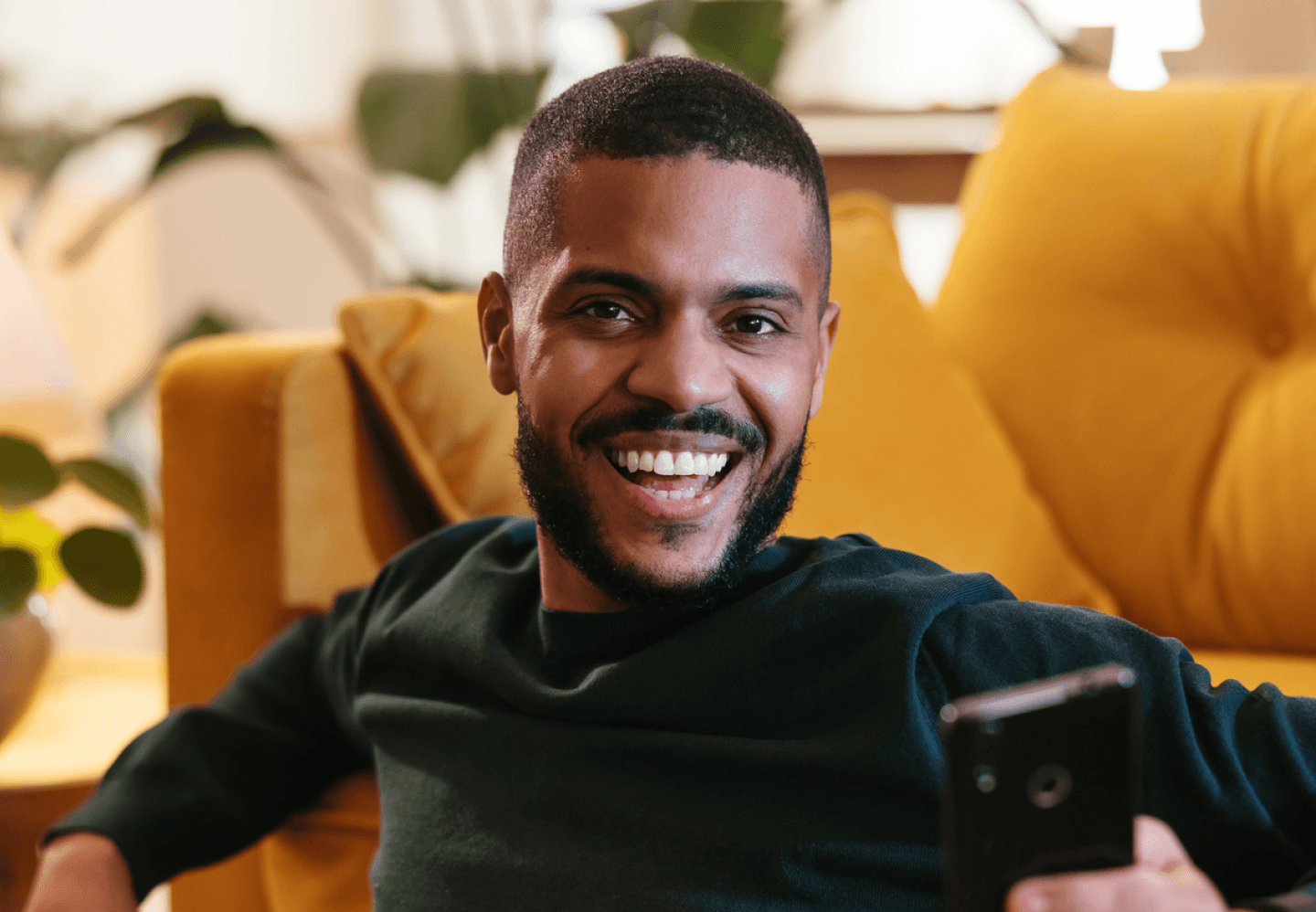 Man sitting on the ground holding a phone smiling