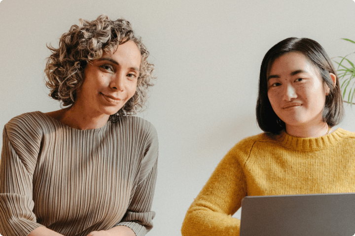 Two women coworkers smiling in warm toned office