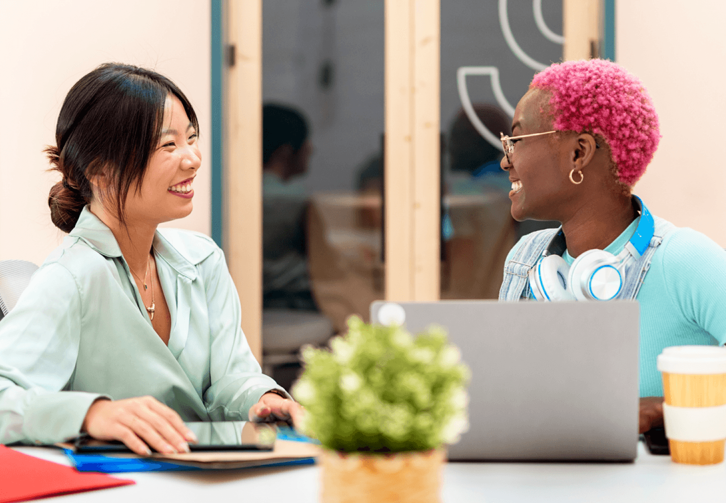 Two women smiling while sitting at a desk in an office setting