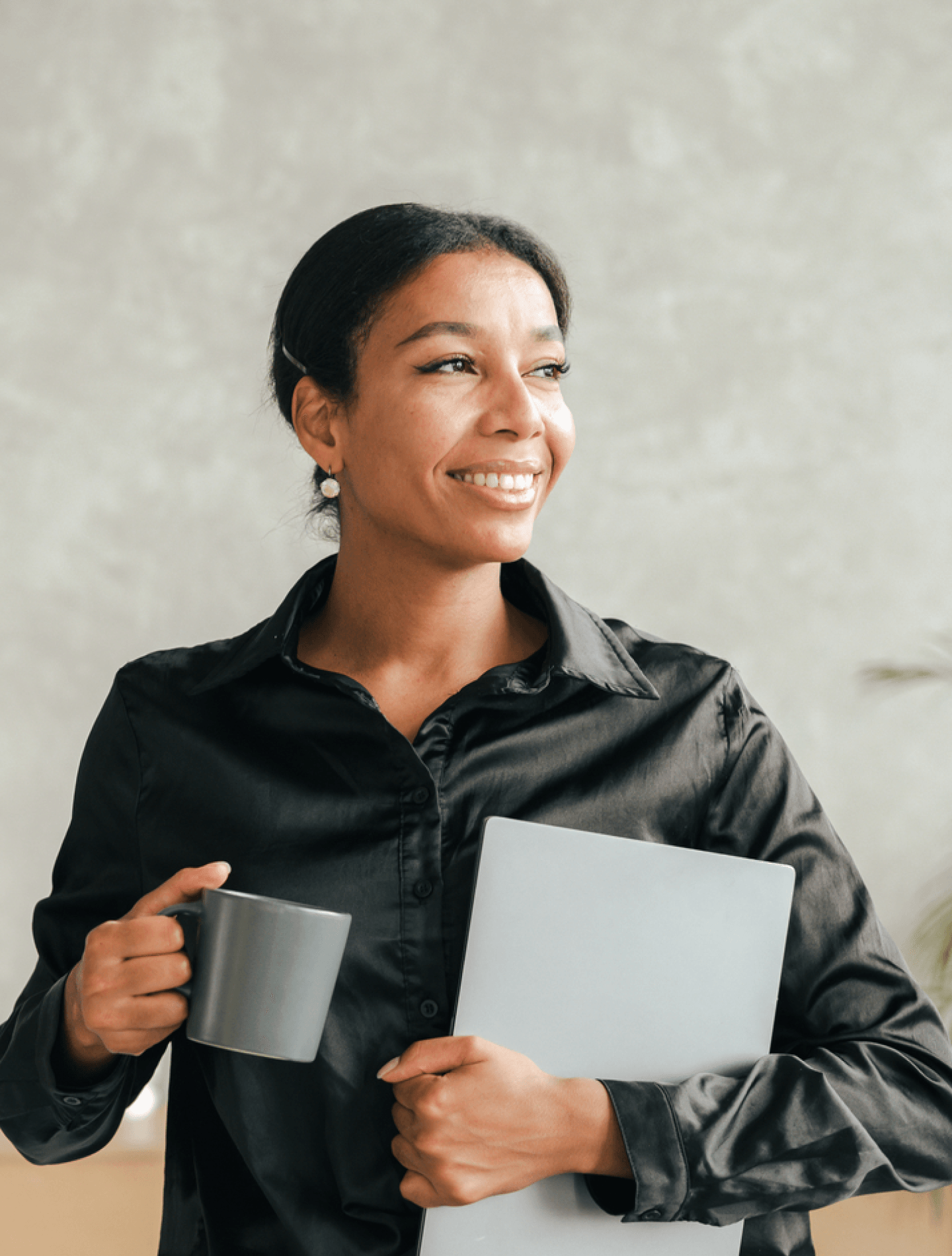 Woman in office smiling holding laptop